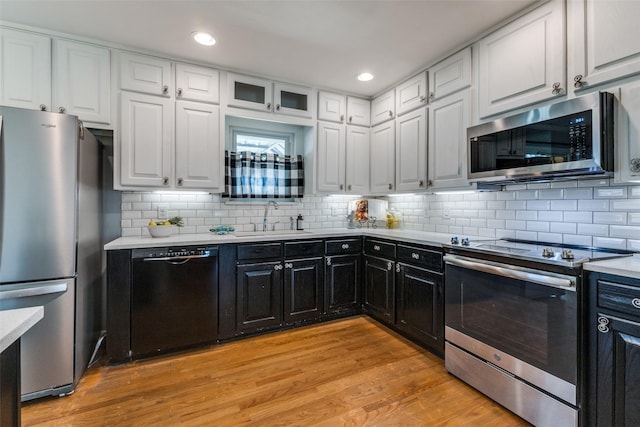 kitchen featuring light wood-style flooring, appliances with stainless steel finishes, light countertops, white cabinetry, and a sink