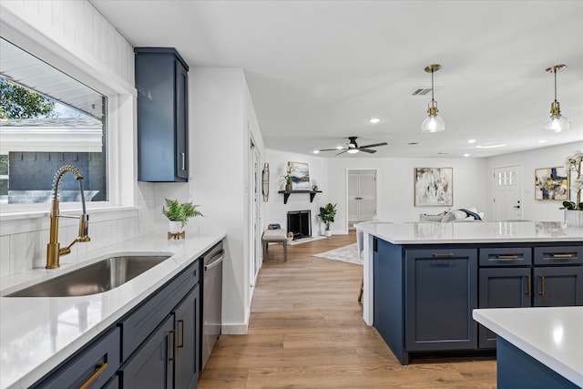 kitchen featuring stainless steel dishwasher, open floor plan, a sink, and light countertops