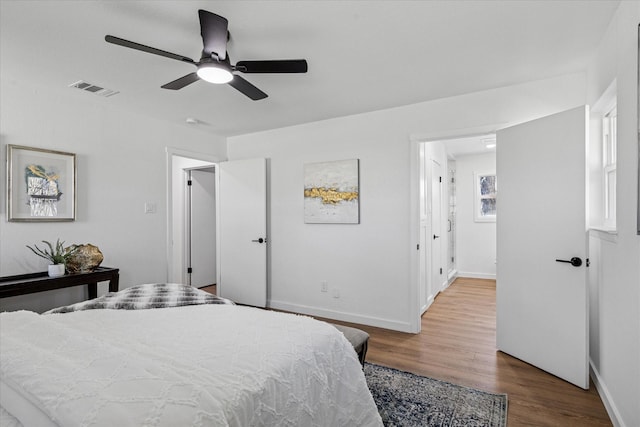 bedroom featuring baseboards, visible vents, ceiling fan, and wood finished floors