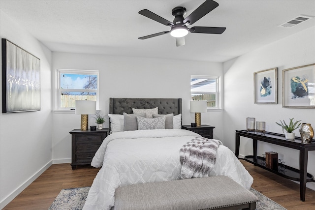 bedroom featuring a ceiling fan, visible vents, baseboards, and wood finished floors