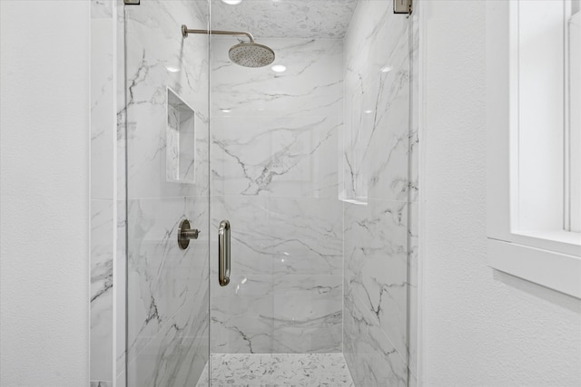 bathroom with a textured wall and a marble finish shower