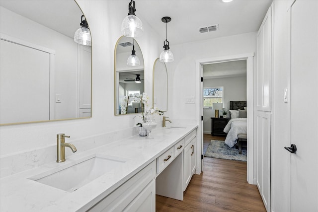 full bathroom with double vanity, wood finished floors, a sink, and visible vents