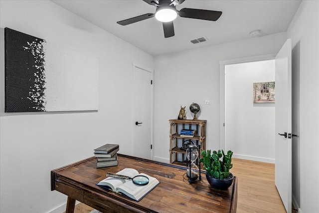 office featuring a ceiling fan, visible vents, baseboards, and wood finished floors