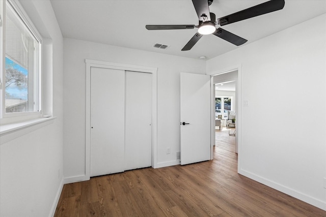 unfurnished bedroom featuring wood finished floors, visible vents, and baseboards