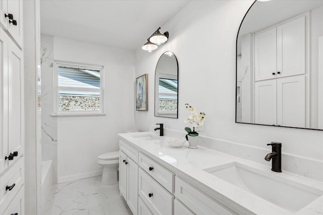 bathroom featuring marble finish floor, a sink, toilet, and a healthy amount of sunlight