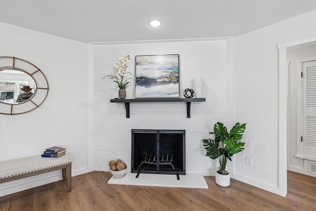 interior space with baseboards, a fireplace with raised hearth, wood finished floors, and recessed lighting