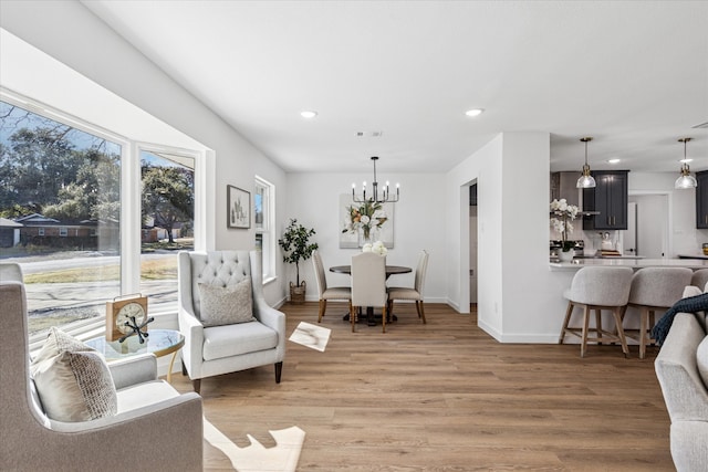 living area with light wood finished floors, recessed lighting, visible vents, an inviting chandelier, and baseboards