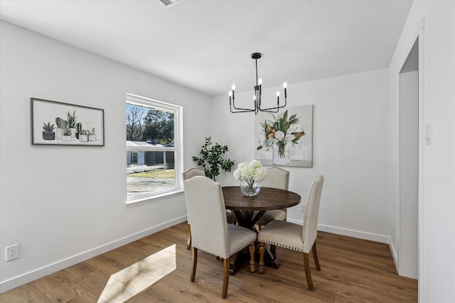 dining area featuring a chandelier, baseboards, and wood finished floors