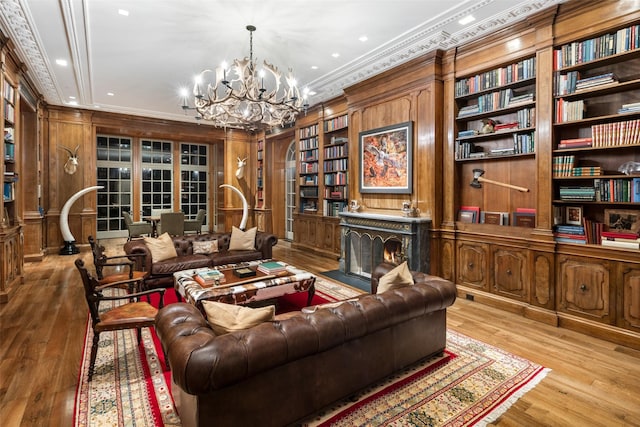 living area featuring wood walls, a fireplace with flush hearth, ornamental molding, and light wood-style flooring