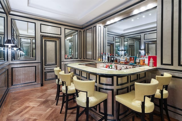 bar featuring ornamental molding, a decorative wall, and indoor wet bar