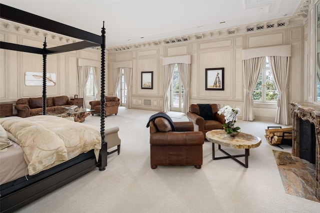 bedroom with light carpet, access to outside, a premium fireplace, and a decorative wall