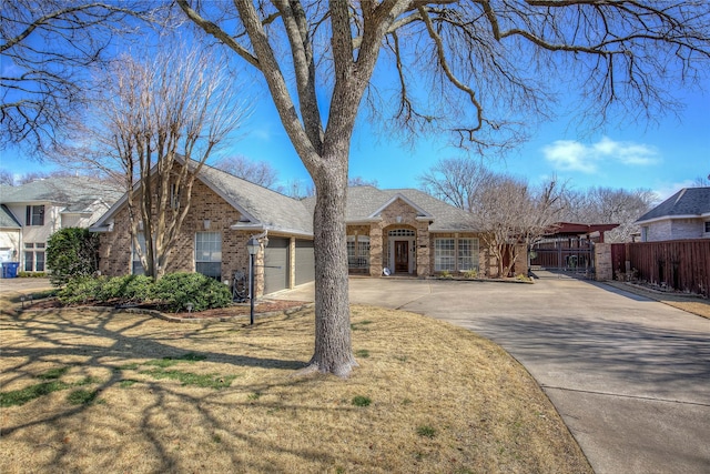 view of front of home with concrete driveway, an attached garage, fence, a front lawn, and brick siding