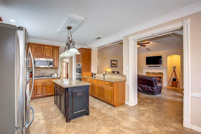 kitchen featuring light stone counters, a center island, stainless steel appliances, hanging light fixtures, and open floor plan