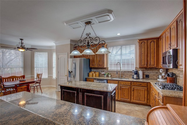 kitchen with stainless steel appliances, a sink, a center island, brown cabinets, and pendant lighting