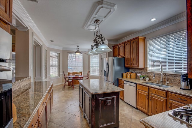 kitchen with a sink, a center island, appliances with stainless steel finishes, brown cabinets, and crown molding