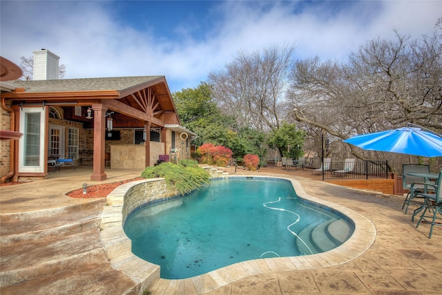 view of swimming pool featuring a fenced in pool, a patio, outdoor dry bar, and fence