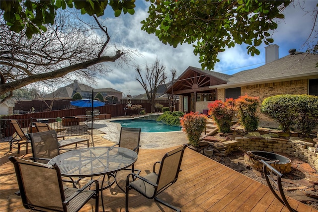 view of swimming pool with an outdoor fire pit, a fenced in pool, fence, outdoor dining area, and a wooden deck