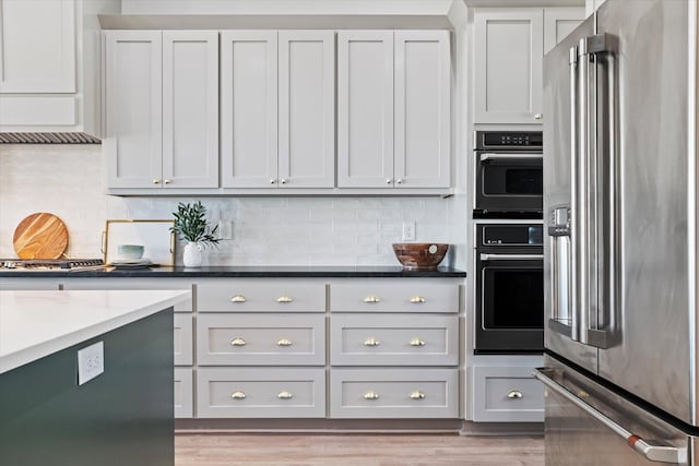 kitchen featuring stainless steel appliances, dark stone counters, gray cabinetry, and tasteful backsplash