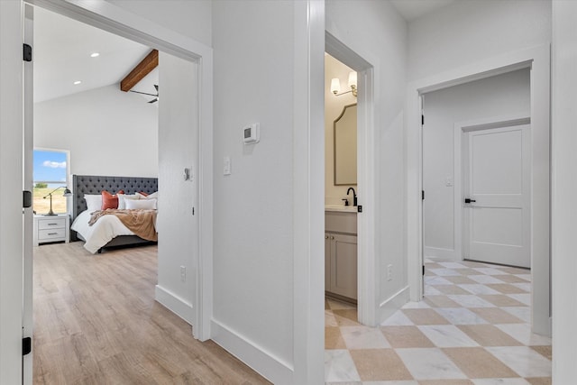 hall with baseboards, lofted ceiling with beams, light floors, a sink, and recessed lighting