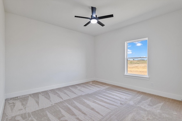 spare room with baseboards, a ceiling fan, and light colored carpet