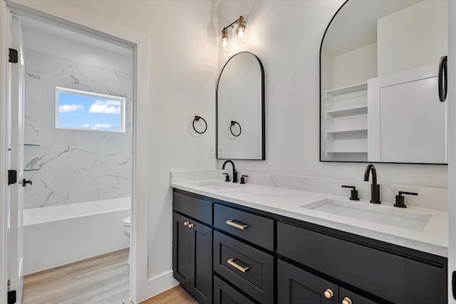 full bathroom with double vanity, toilet, a sink, and wood finished floors