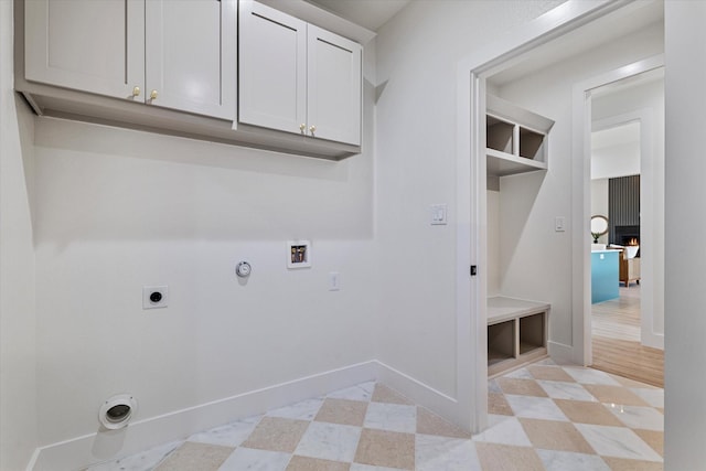 washroom featuring hookup for an electric dryer, washer hookup, baseboards, cabinet space, and light floors