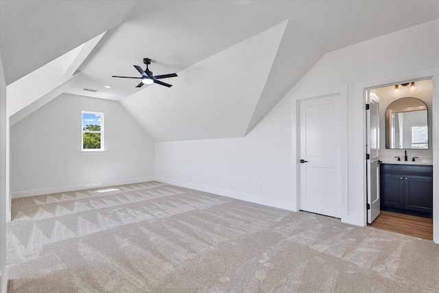 additional living space with lofted ceiling, light carpet, a sink, and visible vents