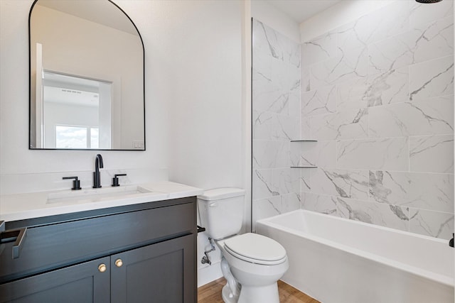 bathroom featuring toilet, shower / bathing tub combination, wood finished floors, and vanity