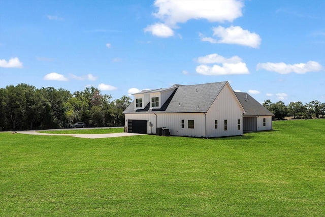 back of property featuring driveway, a shingled roof, a garage, and a lawn