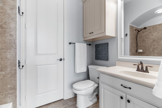 bathroom with tiled shower, vanity, and toilet