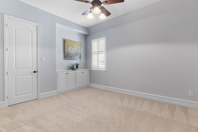 unfurnished room with ceiling fan, baseboards, and light colored carpet