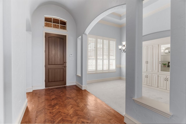 foyer entrance featuring ornamental molding, arched walkways, a notable chandelier, and baseboards