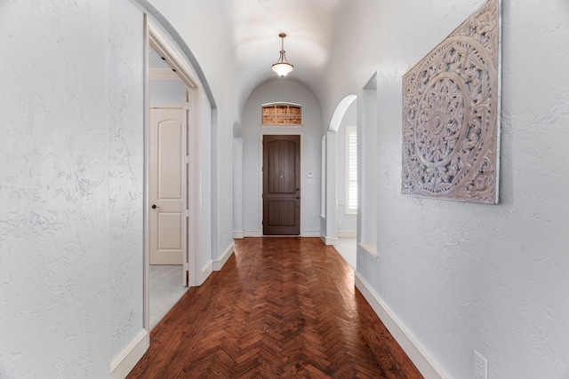 interior space with arched walkways, a textured wall, and baseboards