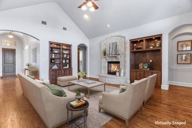 living area with arched walkways, wood finished floors, and visible vents