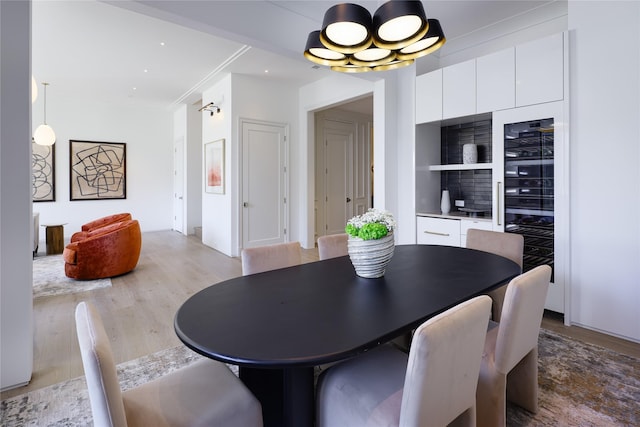 dining area with ornamental molding, light wood finished floors, and wine cooler