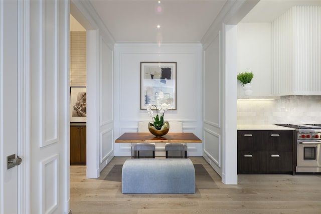 hall featuring crown molding, light wood-style floors, and a decorative wall