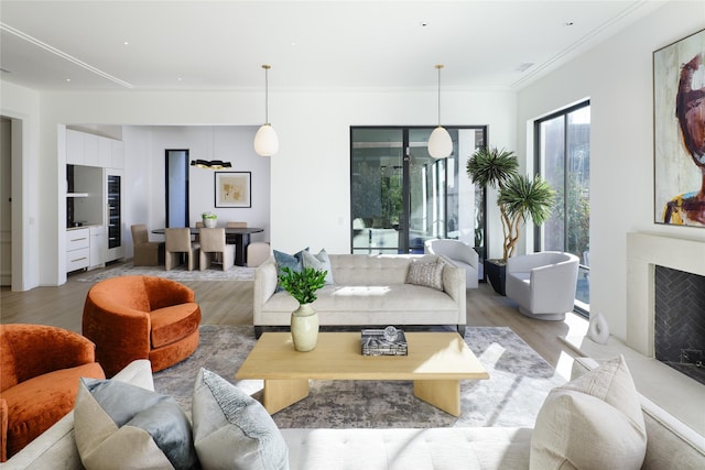 living room featuring light wood-style flooring, a fireplace, and crown molding