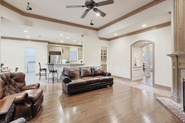 living room featuring light wood finished floors, baseboards, arched walkways, a ceiling fan, and recessed lighting