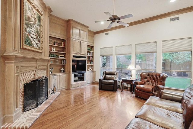 living room featuring built in shelves, visible vents, light wood-style floors, a brick fireplace, and crown molding