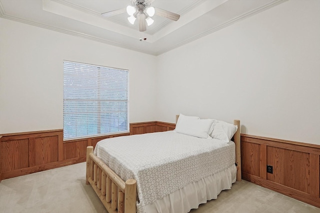 bedroom featuring a wainscoted wall, a raised ceiling, and light colored carpet