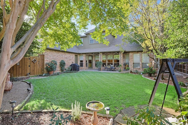 back of property with a shingled roof, a lawn, fence, a patio area, and brick siding