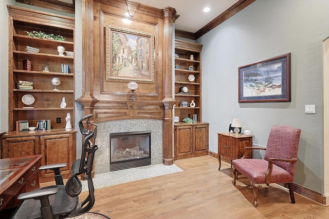 living area with ornamental molding, light wood-type flooring, a fireplace, and baseboards