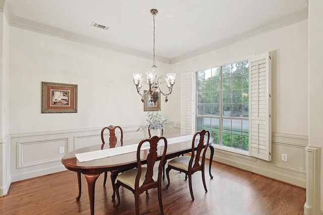 dining space with a notable chandelier, visible vents, wood finished floors, and ornamental molding