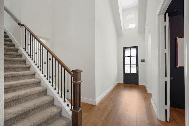 entrance foyer with baseboards, a high ceiling, and light wood finished floors