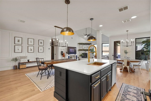 kitchen featuring light countertops, visible vents, a decorative wall, open floor plan, and a sink