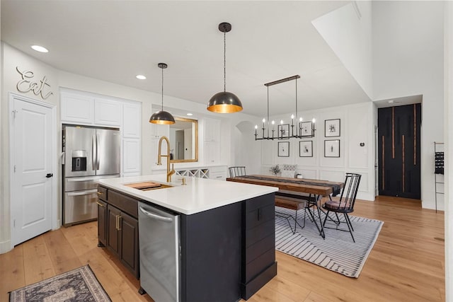 kitchen with arched walkways, light wood finished floors, light countertops, appliances with stainless steel finishes, and a sink