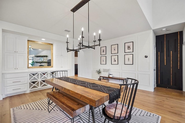 dining room with light wood finished floors, visible vents, and a decorative wall