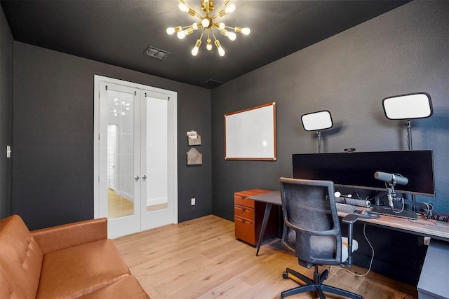 office space featuring light wood finished floors, french doors, visible vents, and a notable chandelier