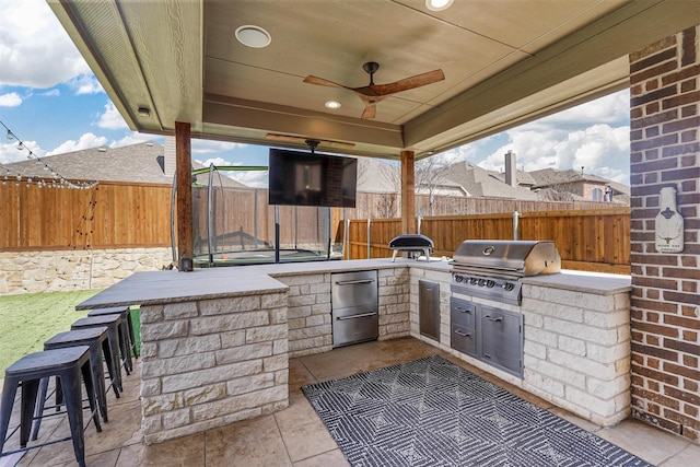 view of patio with outdoor dry bar, a fenced backyard, grilling area, and area for grilling