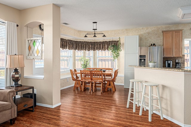 dining room featuring dark wood-style floors, visible vents, baseboards, and a textured ceiling